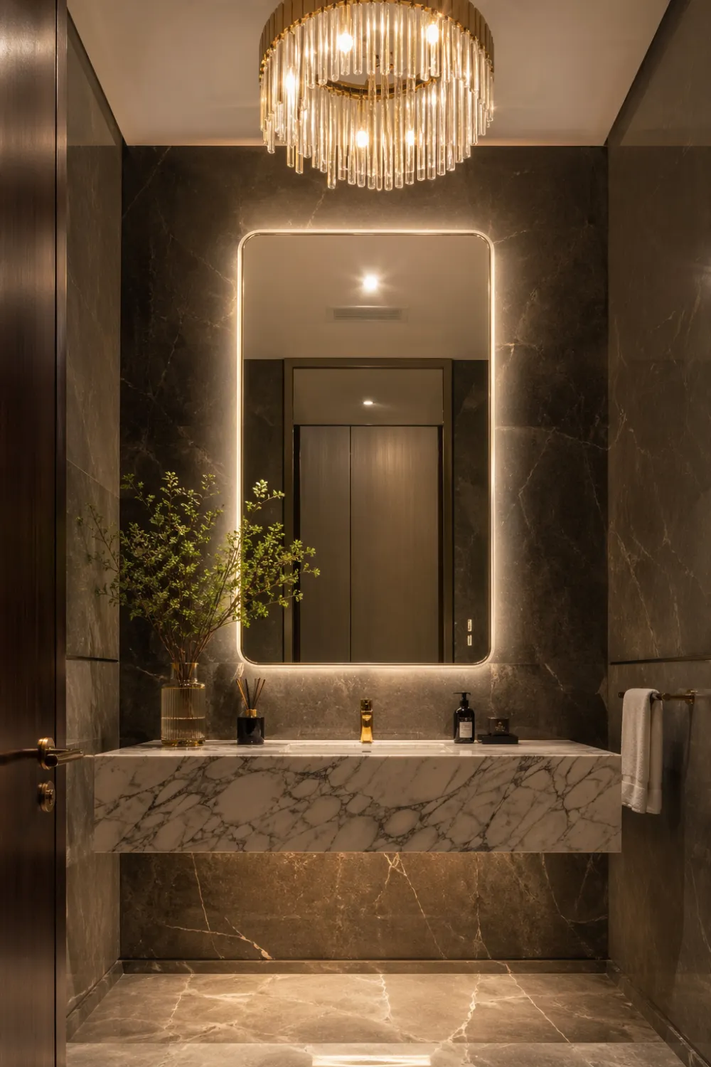 Luxury bathroom with elegant chandelier above mirror creating warm layered lighting and a high end hotel look