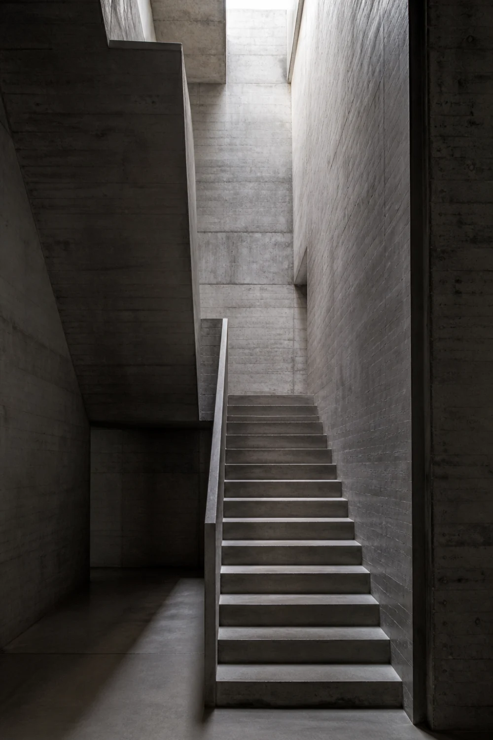 brutalist concrete staircase with raw texture, tall walls, skylight lighting, modern industrial interior design