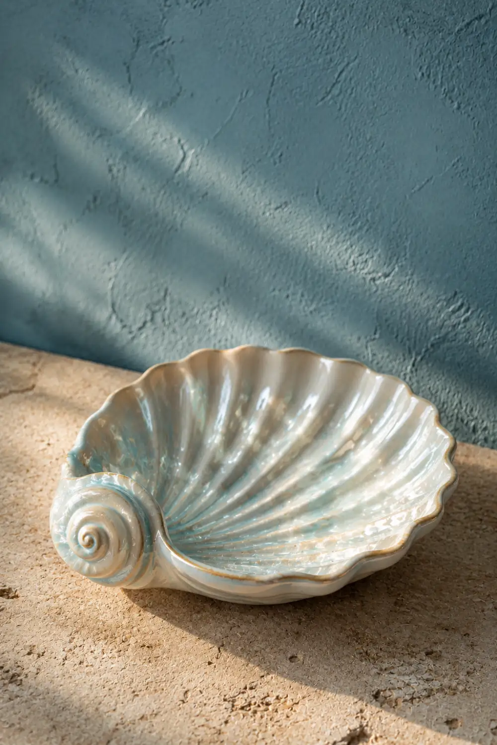Seashell inspired clay trinket tray with glossy coastal finish displayed on a textured stone surface. Handmade pottery decor idea for beach house interiors, jewelry storage, bathroom styling, and coastal home decor.