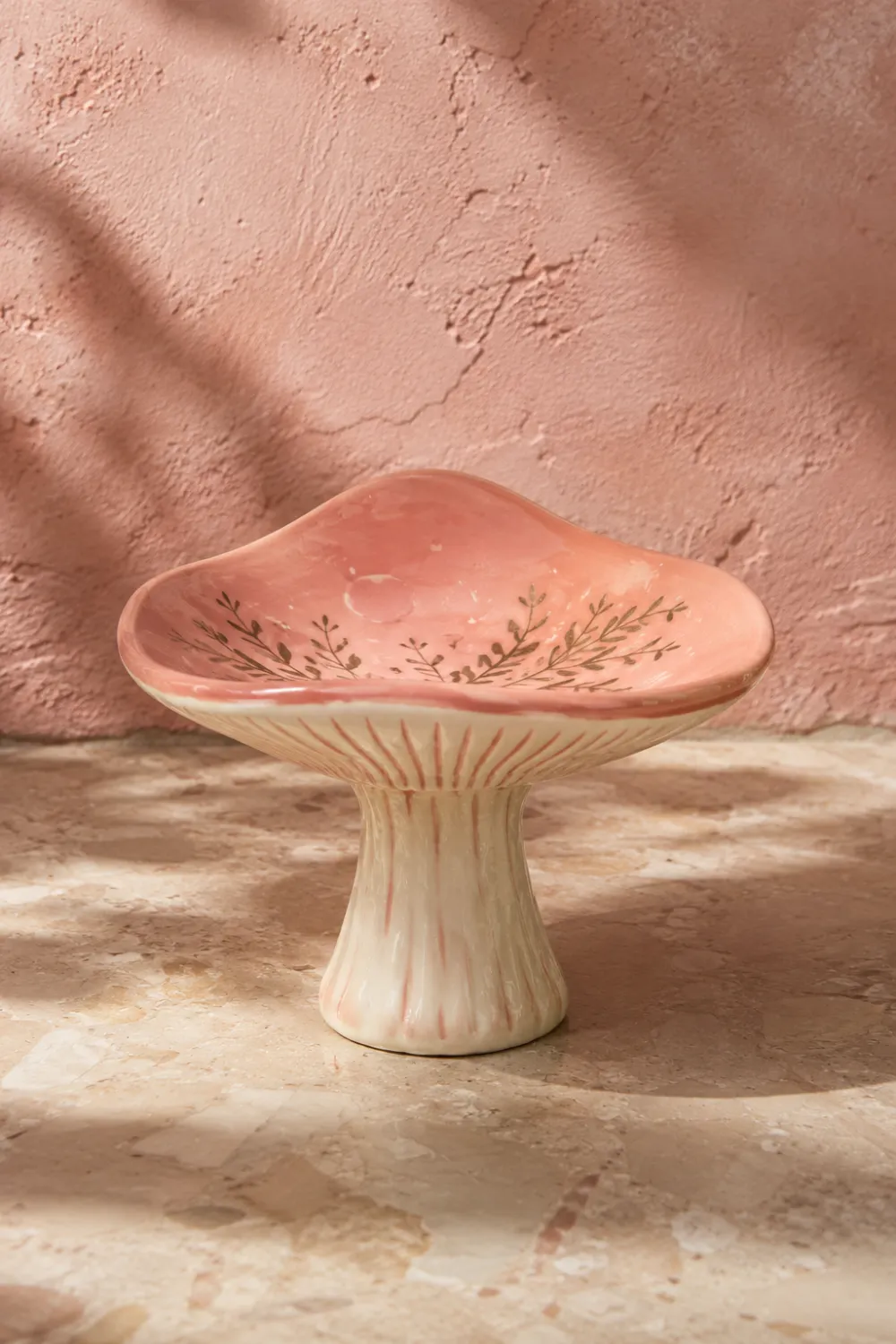 Pink mushroom shaped clay trinket dish with delicate botanical details displayed on a stone surface. Beautiful handmade pottery decor for jewelry storage, bedroom styling, vanity decor, cottagecore interiors, and whimsical home decorating ideas.