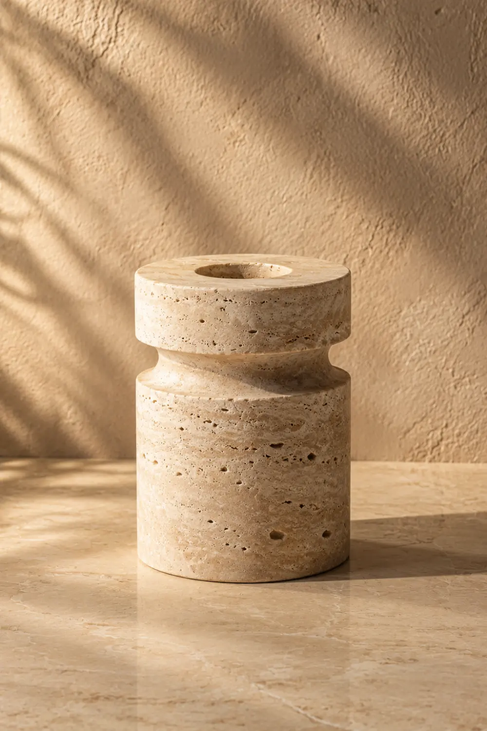Minimalist travertine stone candle holder with natural texture displayed on a polished stone surface in a luxury modern home decor setting