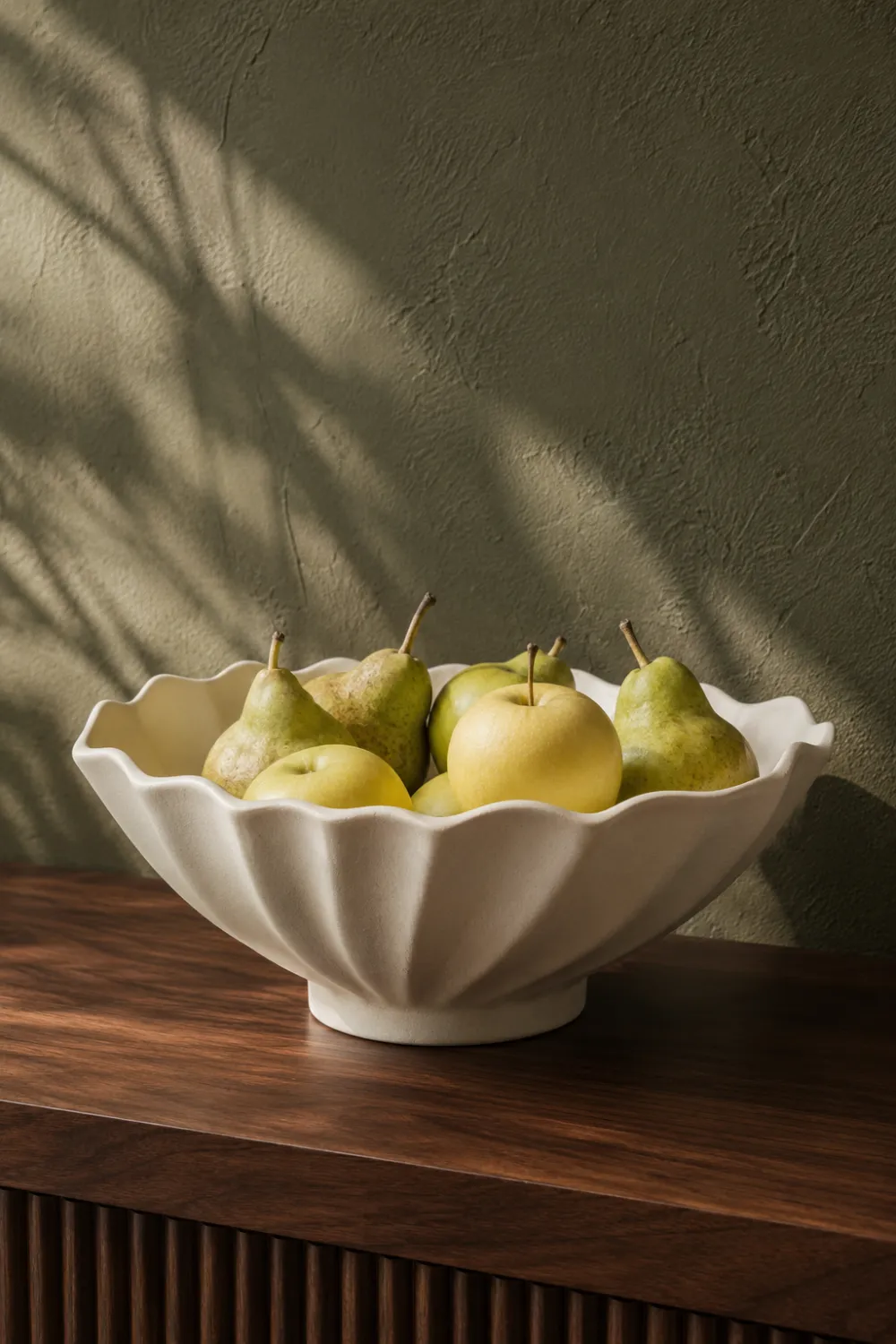 Decorative fluted ceramic fruit bowl filled with fresh pears and apples on a walnut console table in a modern luxury home interior