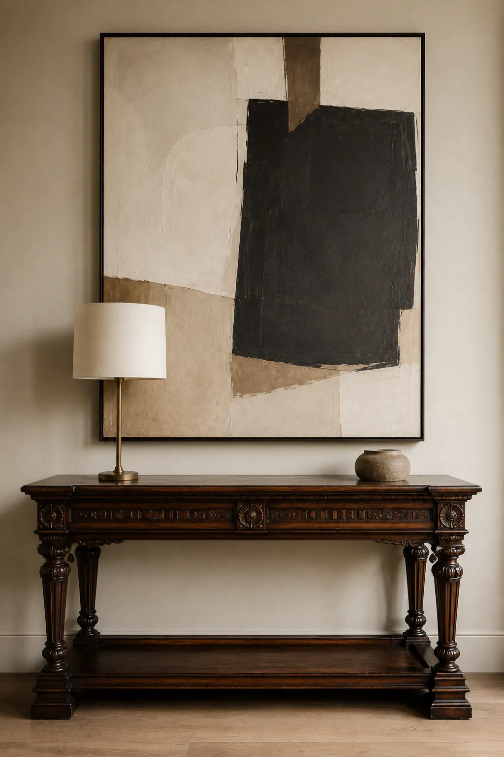 Ornate dark walnut antique console with carved legs and detailed traditional craftsmanship paired with oversized contemporary abstract artwork, a slim modern brass lamp, and a minimalist ceramic vase in a refined neutral entryway.