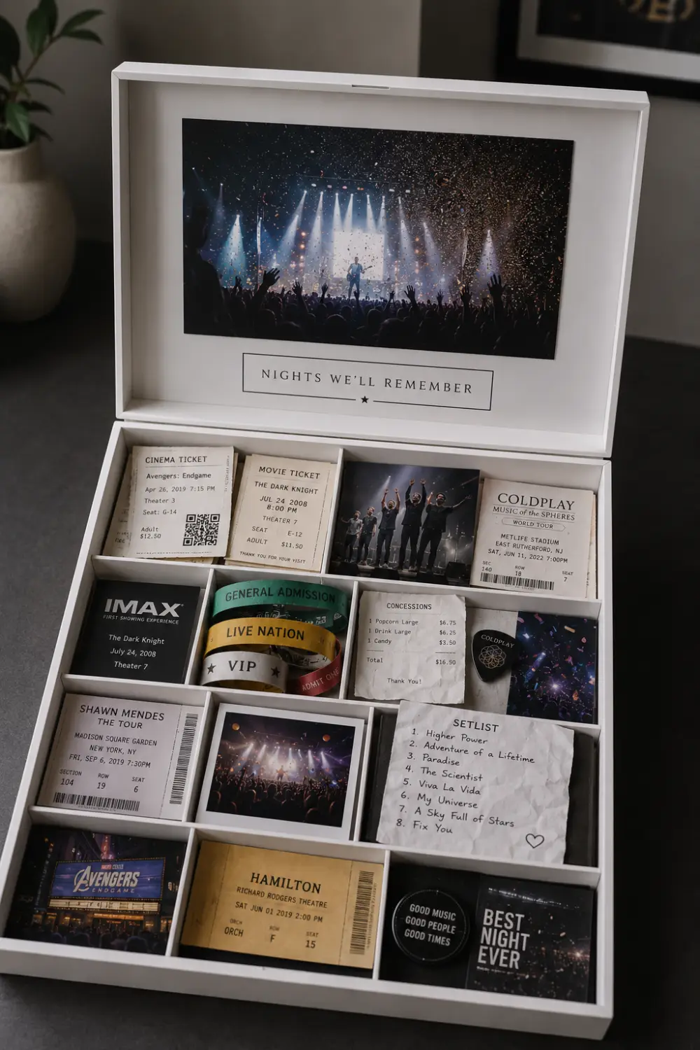 Modern movie and concert memory box displayed open with cinema tickets, concert passes, event wristbands, music photographs, movie receipts, setlists, theater tickets, and small entertainment souvenirs arranged in organized sections
