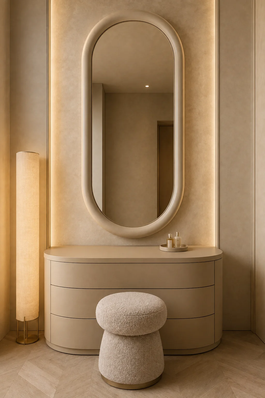 Warm curved vanity aesthetic featuring a custom rounded vanity console with smooth curved edges and seamless drawers, a tall oversized arched mirror with a thick sculptural cream frame, soft backlighting around the mirror, a textured warm beige wall with subtle architectural detailing, a tall contemporary floor lamp with a glowing fabric shade and slim champagne gold base, a small rounded cream bouclé vanity stool with a gold pedestal base, a minimal perfume tray, soft beige cabinetry, warm wood flooring, and layered ambient lighting creating an elegant, cozy, luxurious beauty corner.