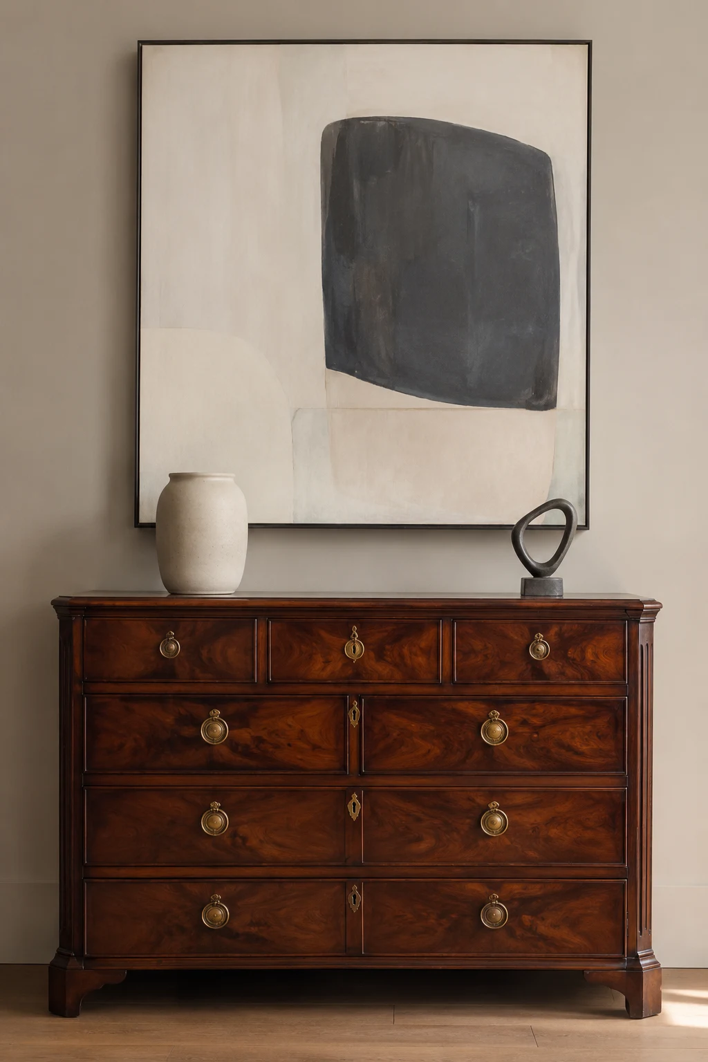 Rich dark walnut antique chest with detailed wood grain, traditional brass hardware, and classic proportions styled as a modern sideboard beneath oversized contemporary abstract artwork with minimal ceramic decor.