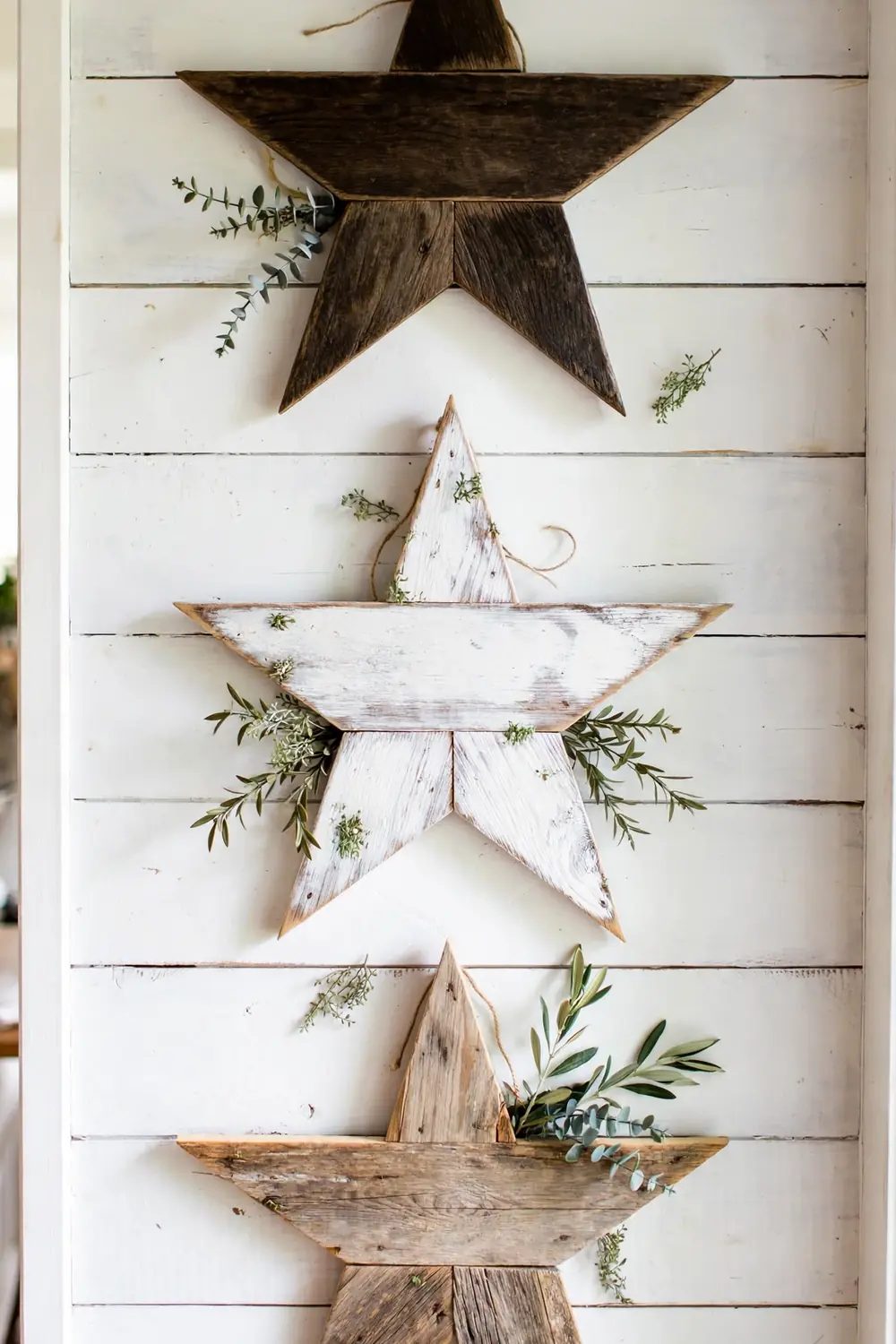 Reclaimed wood stars arranged on a farmhouse gallery wall with greenery, Christmas star decor ideas